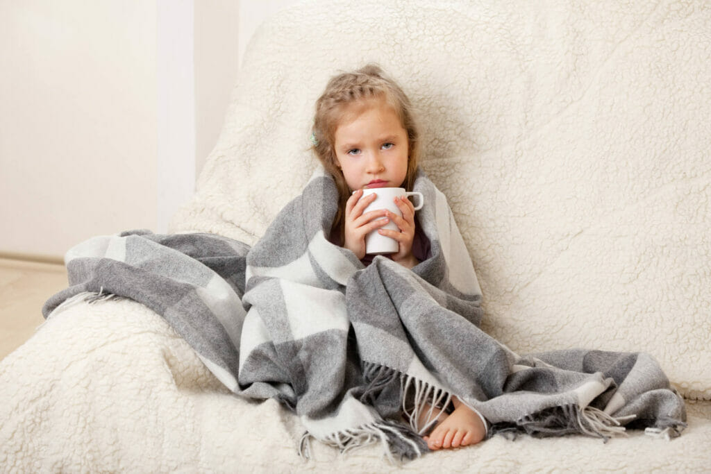 Un bambino con l'influenza regge una tazza di una bevanda calda
