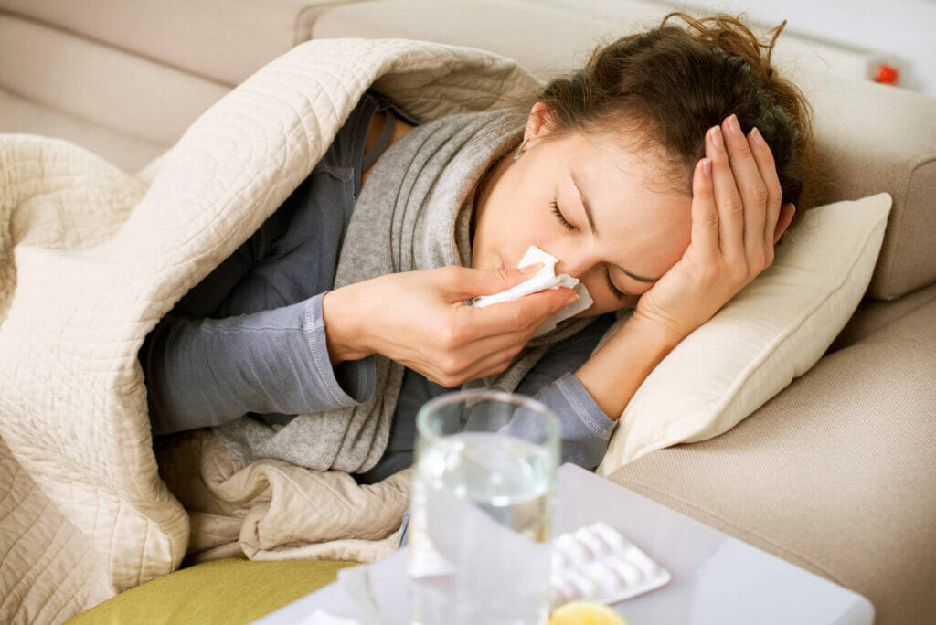 Una ragazza colpita da una patologia stagionale si soffia il naso a letto
