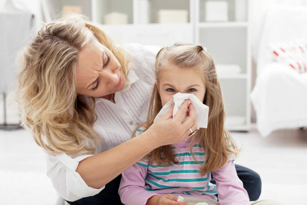 Una madre fa soffiare il naso alla propria figlia colpita da allergia stagionale