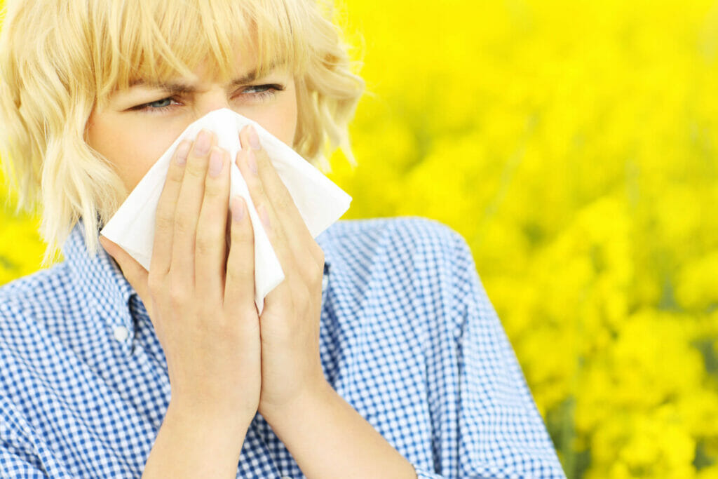 Una signora in preda a una allergia di primavera si soffia il naso